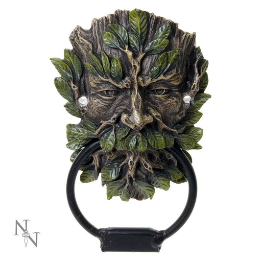 A door knocker depicts a face with intricately carved leaves resembling hair and beard, holding a black metal ring. The design combines rustic and mythical elements. Marked with "N * N" insignia.