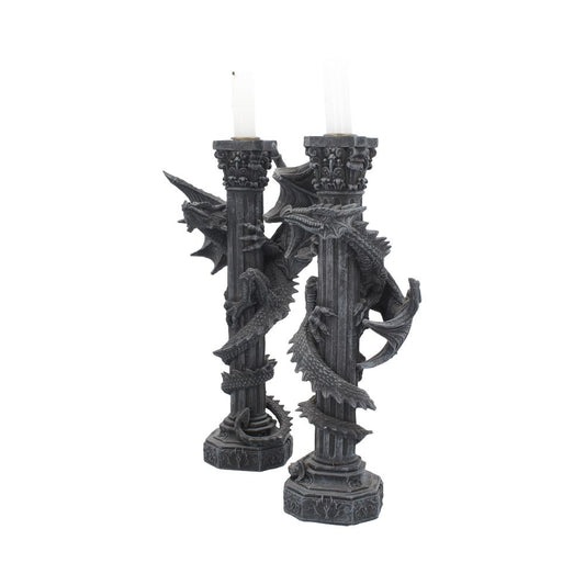 Gothic stone pillar candle holders with dragons coiling around them hold white candles against a plain white background.