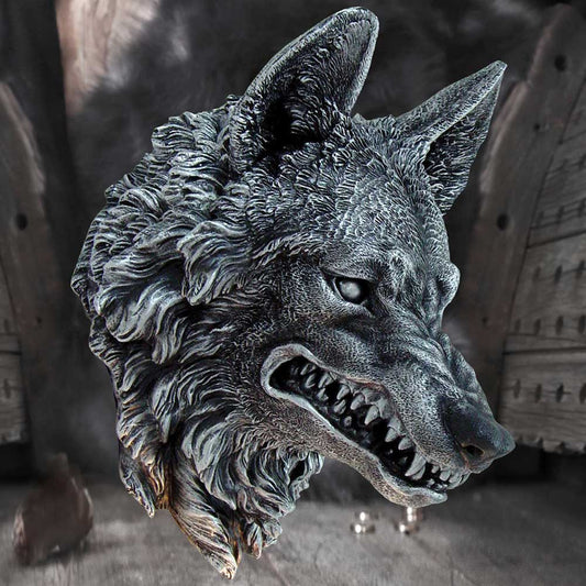A detailed stone sculpture of a snarling wolf's head is depicted, showing sharp teeth and intense eyes, situated against a shadowy background of rustic wooden doors and a dimly lit, rocky ground.