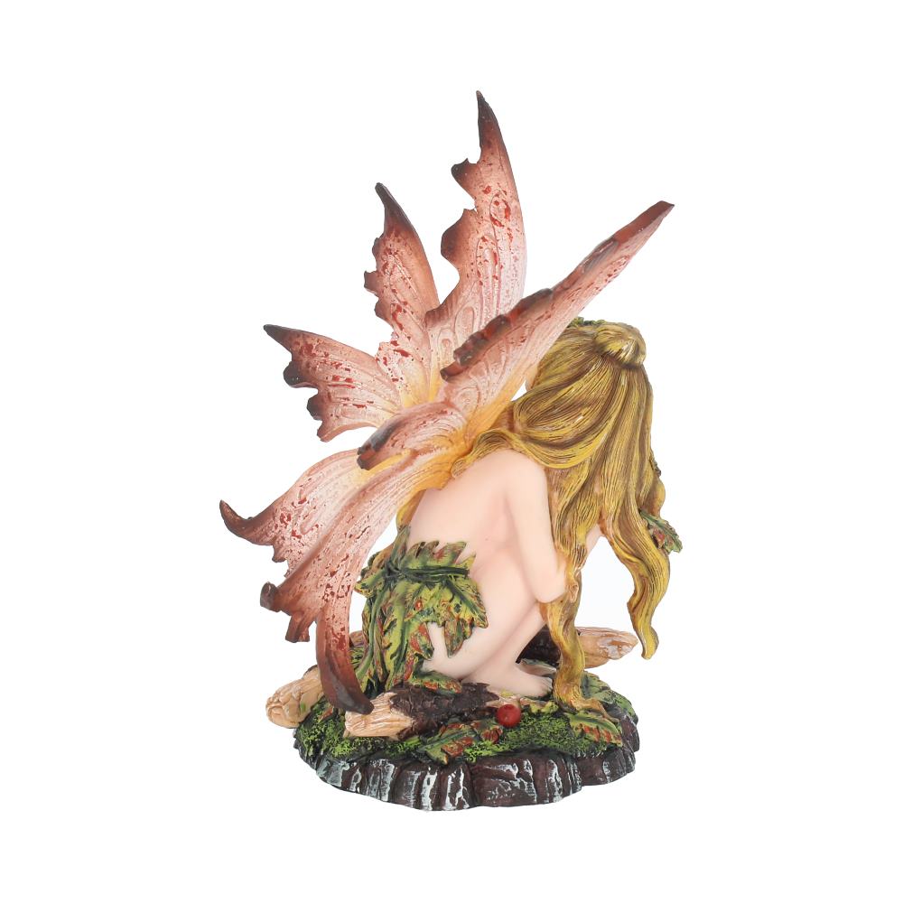A fairy figurine crouches among leaves and berries, gazing downward. She has large, orange wings with petal shapes and long, blond hair.