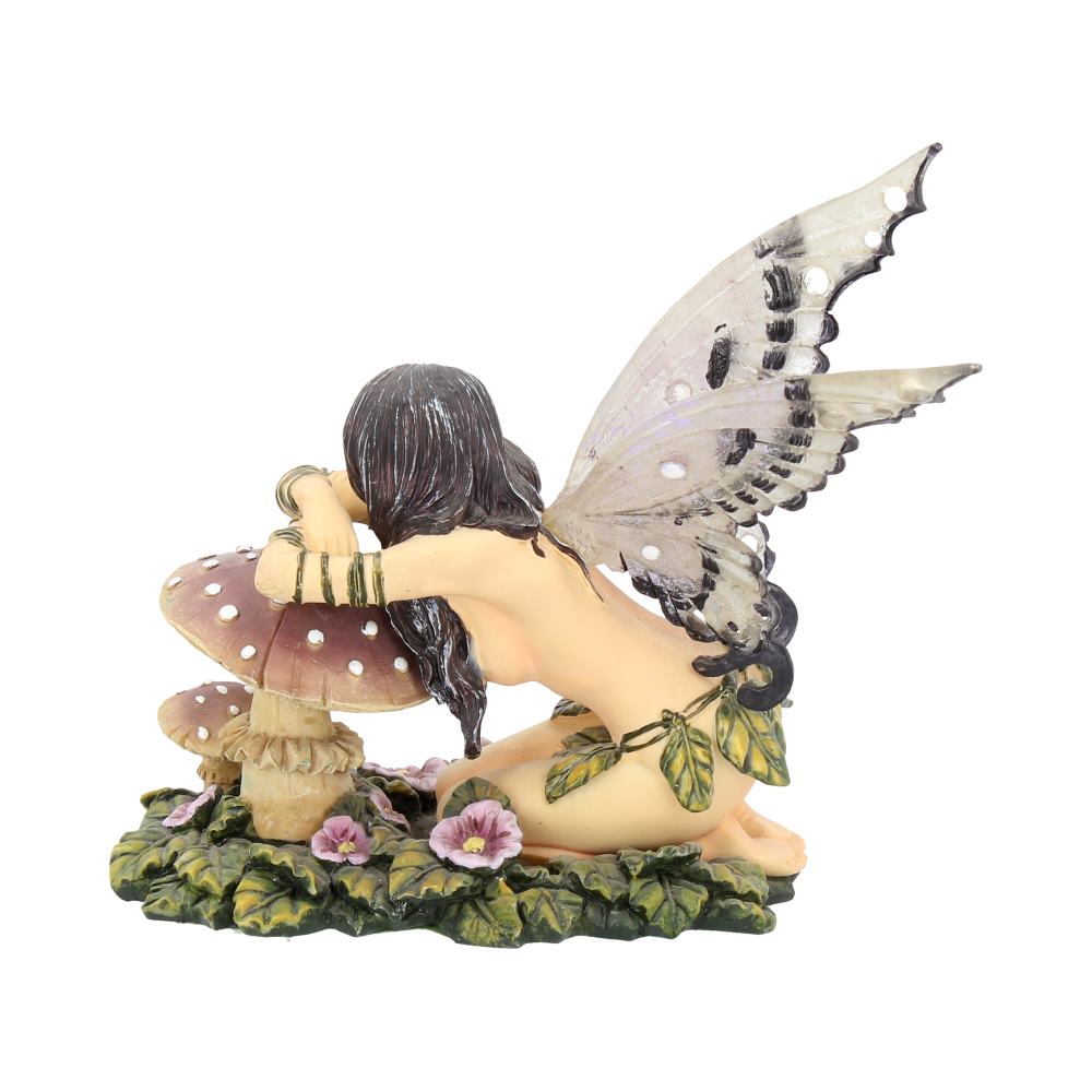 A kneeling fairy leans against a large mushroom. She has butterfly wings and is surrounded by green leaves and pink flowers.