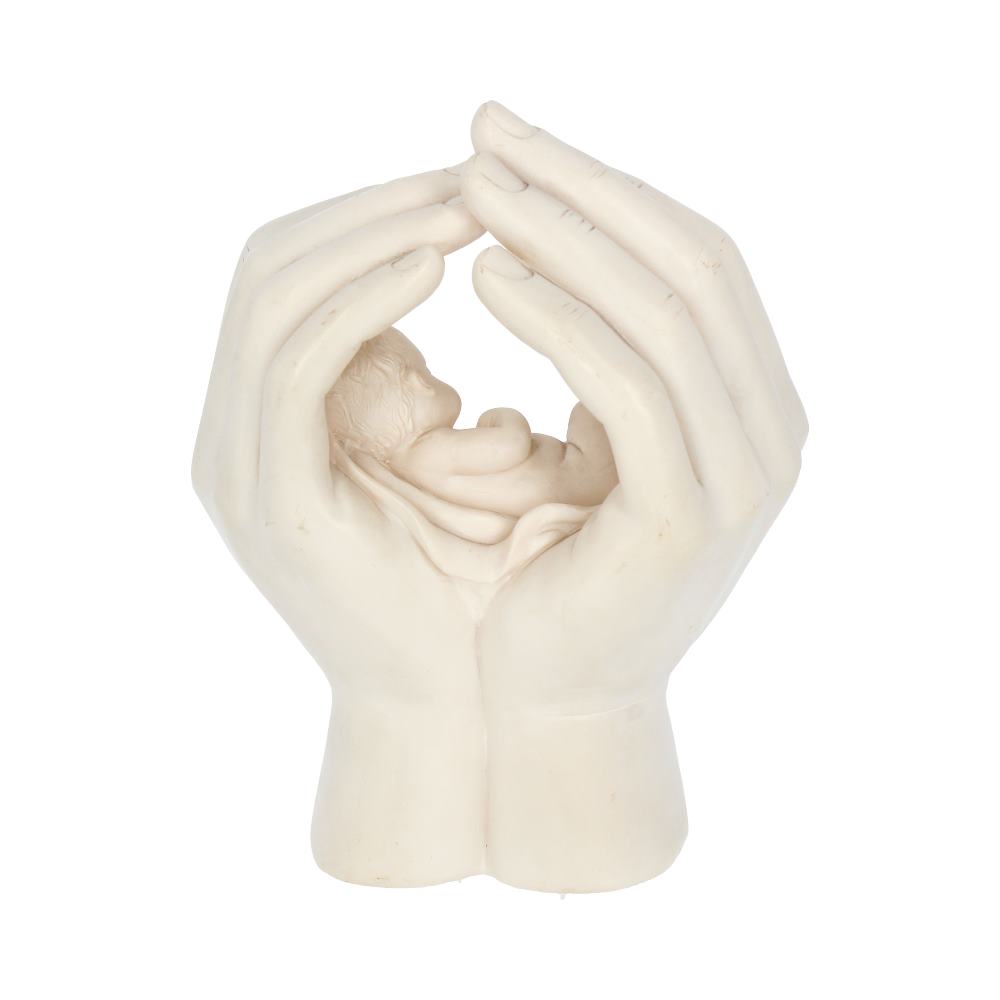 A statue depicts a newborn cradled within cupped hands, fingers lightly touching above, against a white background.