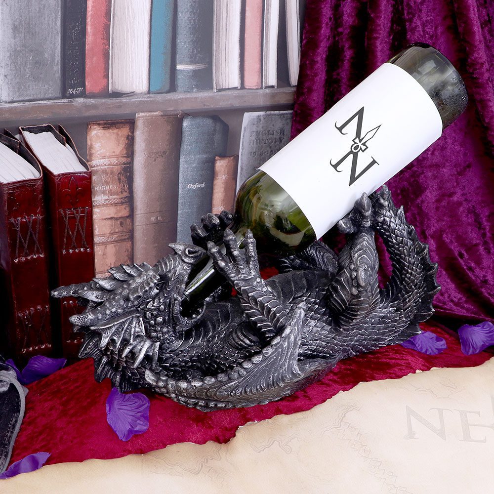 A dragon-shaped wine holder cradles a wine bottle.  The bottle label displays a stylized "NZ" monogram with a spear.  The scene is set against a backdrop of bookshelves and a dark purple fabric.