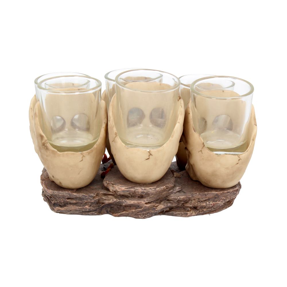 Four glass cups are cradled by beige hands, resting on a textured, brown, rocky base.
