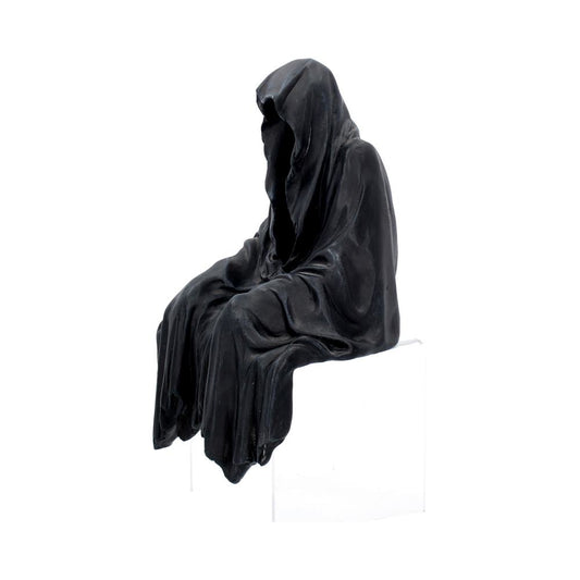 A dark, hooded figure is sitting, draped in flowing garments, on a stark, white background. The figure appears shrouded and mysterious, creating a somber and contemplative atmosphere.