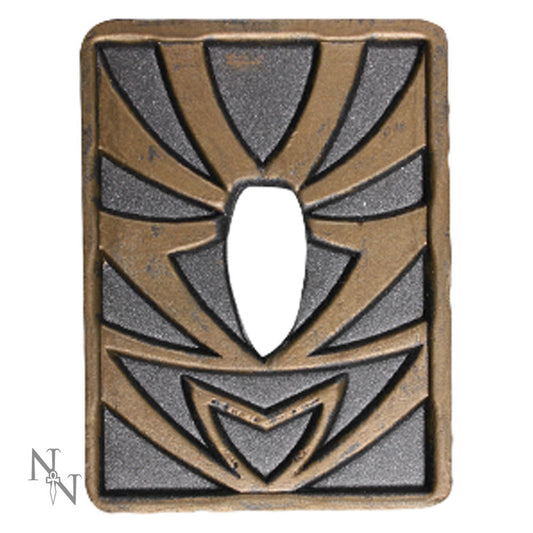 A bronze and gray rectangular metal object with geometric cutouts and designs, surrounding a central oval opening. The background features a subtle logo combining "N" and "T".