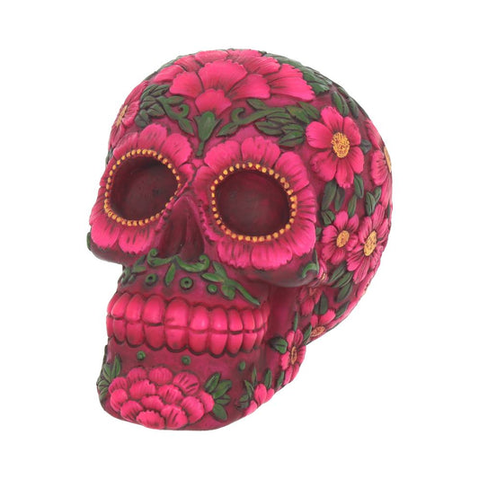 A decorated skull with bright pink and green floral patterns covers it, featuring detailed flowers and designs, set on a plain white background.