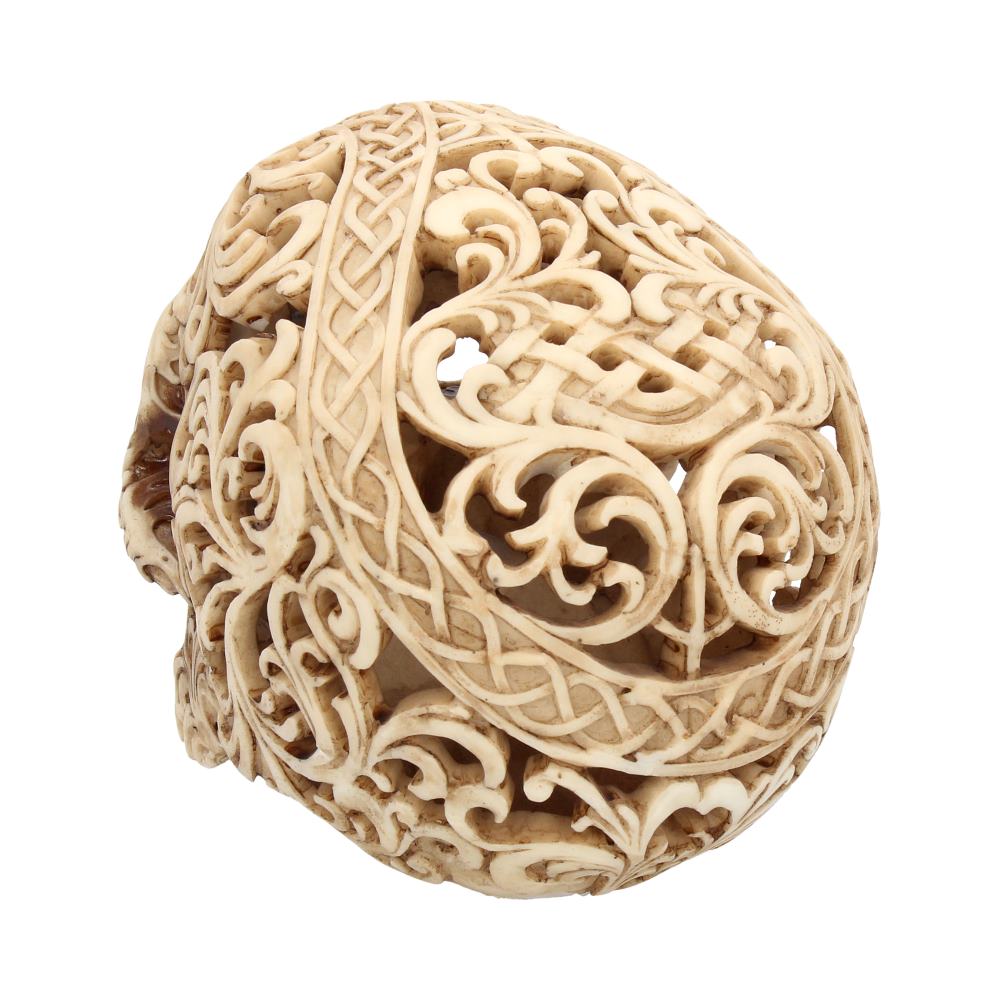 An intricately carved bone skull features elaborate swirling patterns and Celtic knots, set against a plain white background.
