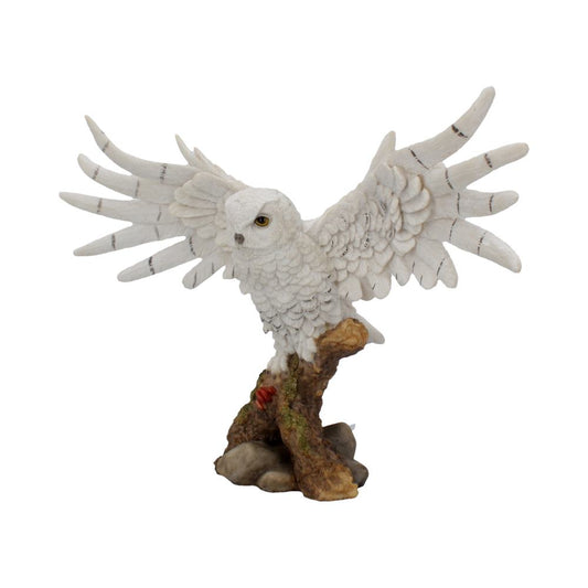 A white owl figurine, wings spread wide, perches on a textured branch. The branch rests on rocks with patches of moss, suggesting a natural forest environment.