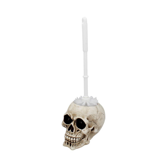 A toilet brush stands upright in a skull-shaped holder, featuring realistic crack details. The bristles emerge from the top, with a white handle extending upward. The background is plain white.