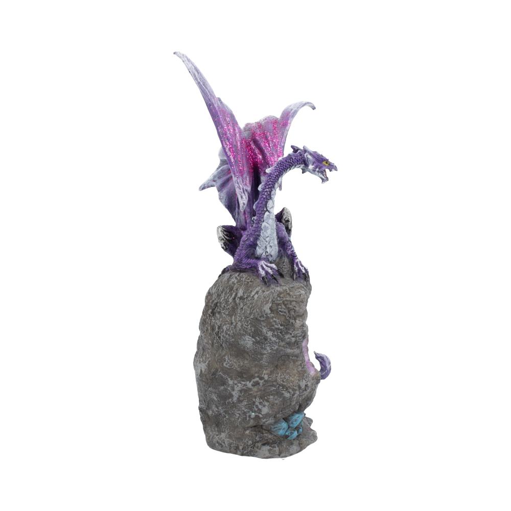 A purple dragon figurine with vibrant wings is perched on a gray rock. The dragon appears fierce, with its mouth open, in a fantastical setting.