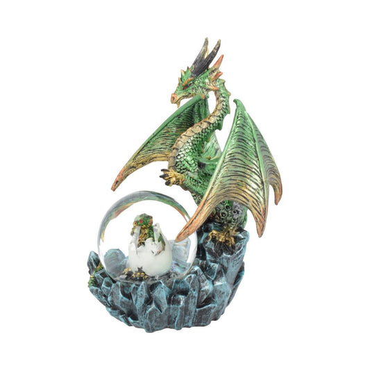 A green dragon figurine stands over a snow globe containing a baby dragon hatching; it is perched atop a sculpted rock base.