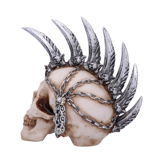 A detailed skull sculpture features metallic wings and chains adorning its surface, set against a plain white background, creating a striking and gothic aesthetic.