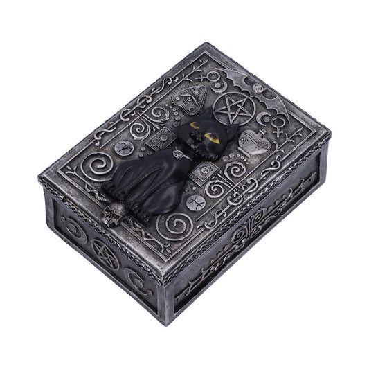 A rectangular, ornate box features a black cat with yellow eyes lying amid intricate designs and symbols, including a pentagram on a metallic, carved surface.