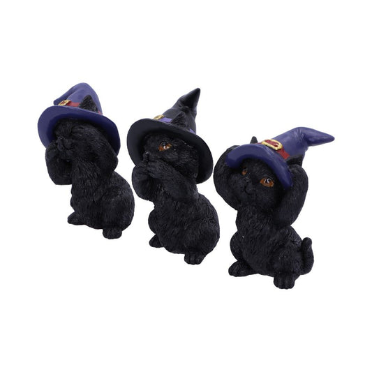 Three black cat figurines wear purple witch hats and cover eyes, mouth, and ears, resembling "see no evil, hear no evil, speak no evil." They sit closely together on a white background.