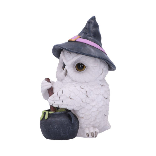 A white owl figurine wears a black witch hat and stirs a green potion in a cauldron, set against a plain white background.