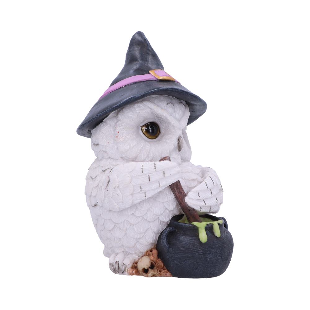 A white owl figurine stirs a green potion in a black cauldron, wearing a black witch hat with a purple band, against a plain white background.