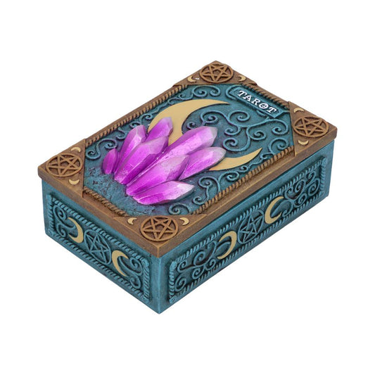 A decorative box with embossed patterns features a cluster of purple crystals and a crescent moon design. The word "TAROT" appears on the lid, set against an ornate blue and gold background.
