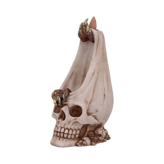 A decorative skull-shaped incense holder with dragon-like claws supports a cone incense at the top. It rests on small skulls, creating a mystical and macabre atmosphere.