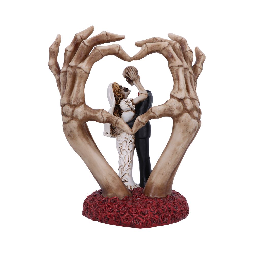 A skeletal bride and groom figurine embrace within large skeletal hands forming a heart shape, set on a textured red rose base, symbolizing eternal love and unity.
