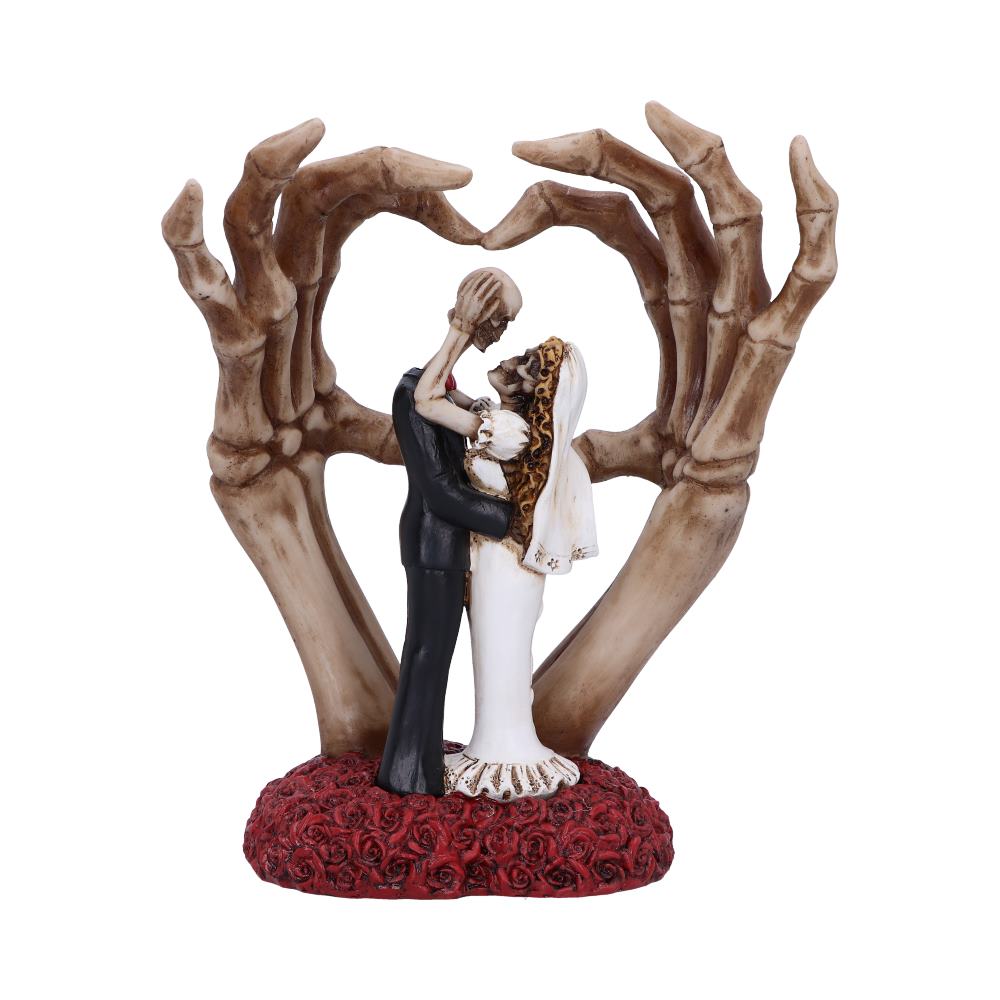 Skeleton couple figurines in a wedding embrace on a base of red roses, with large skeletal hands forming a heart shape behind them, creating a romantic, eerie scene.