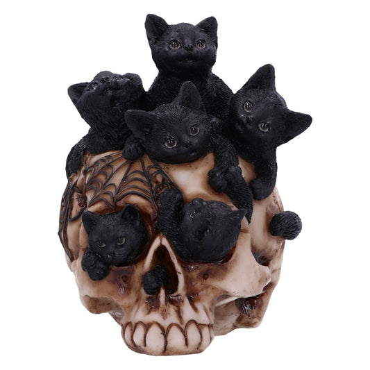 Black cat figurines rest on a skull with spider web designs, depicting a spooky and whimsical scene. The skull serves as the central base for the playful cats.