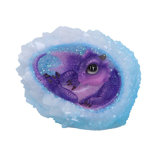 A small, purple dragon figurine rests curled inside a geode-like structure with sparkling blue and white crystals. The setting suggests a mystical or fantasy-themed environment.