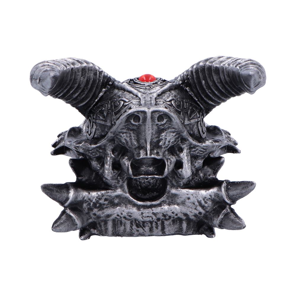 A metallic goat head sculpture features intricate carvings and prominent horns, adorned with a red gem, set against a plain white background.