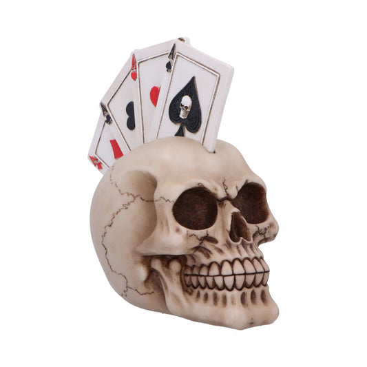 A realistic skull sculpture with a fan of playing cards, including an ace, embedded on top, set against a plain white background.
