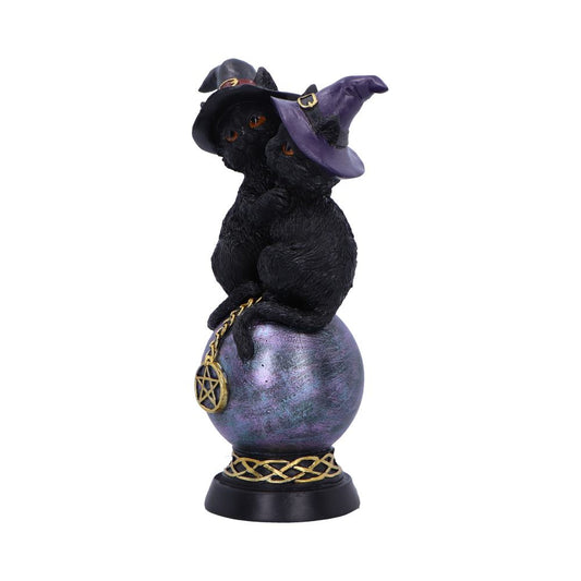 Two black cat figurines in witch hats sit atop a purple iridescent orb with a gold pentagram chain and ornate Celtic knot base on a white background.