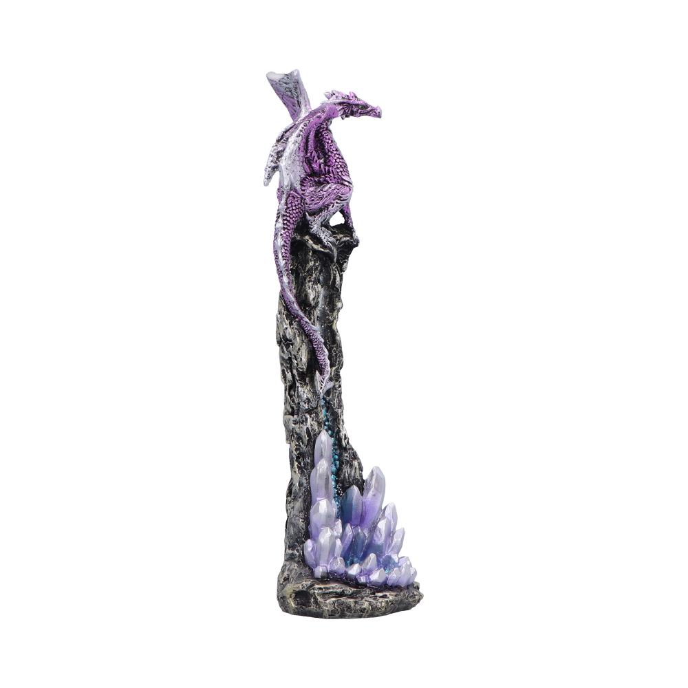 Purple dragon figurine clings to a tall jagged rock spire, tail wrapped down the column above a cluster of iridescent violet crystals against a plain white background.