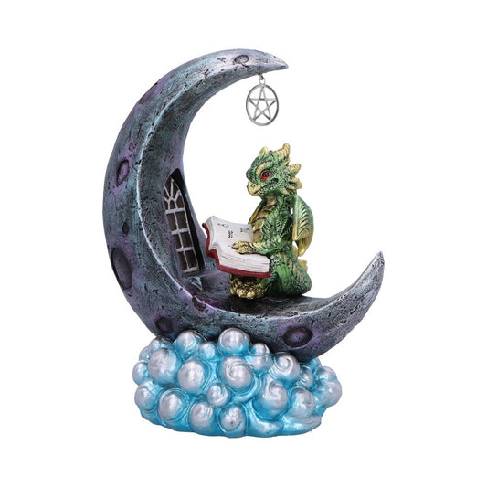 Green dragon figurine reads an open book while sitting inside a textured crescent moon with a dangling pentacle, balanced atop a blue pearlescent cloud base.