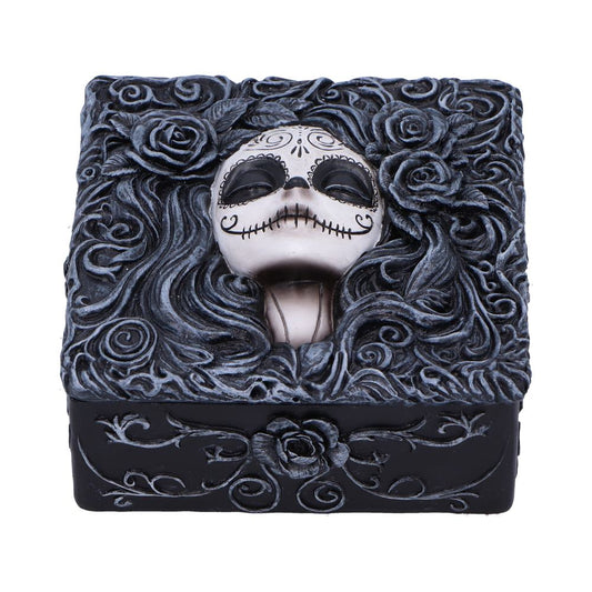 A decorative black resin box displays a silver skull mask with stitched-mouth motifs nestled among swirling carved roses and flowing hairlike vines across the ornate lid.