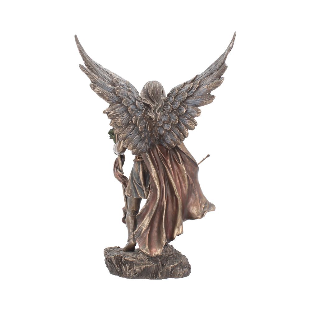 A bronze-colored angel statue, with large wings spread wide, stands on a rocky base, holding a staff. The angel wears a flowing cape, in a poised and majestic manner.