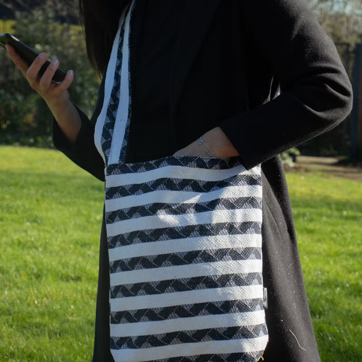 Atlas Nomad Carryall sling bag in black and natural cotton-viscose jacquard with woven striped pattern