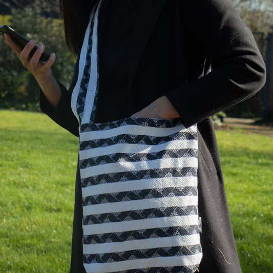 Atlas Nomad Carryall sling bag in black and natural cotton-viscose jacquard with woven striped pattern