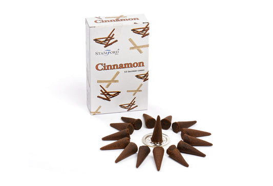 A box labeled "Cinnamon 15 incense cones" by Stamford Inc. is next to an arrangement of brown incense cones in a circular pattern on a white surface.