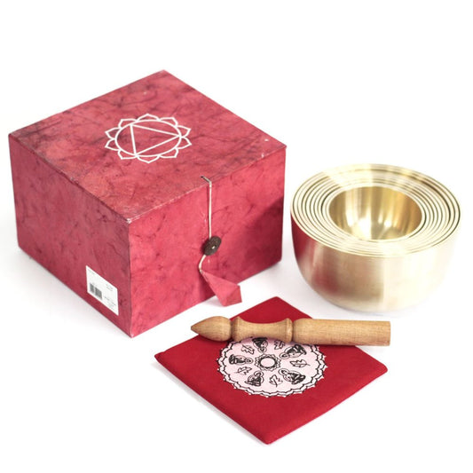 Brass singing bowls rest beside a red decorative box and a small wooden mallet. Below lies a red cloth with a white mandala pattern, creating a serene, ritualistic setting.