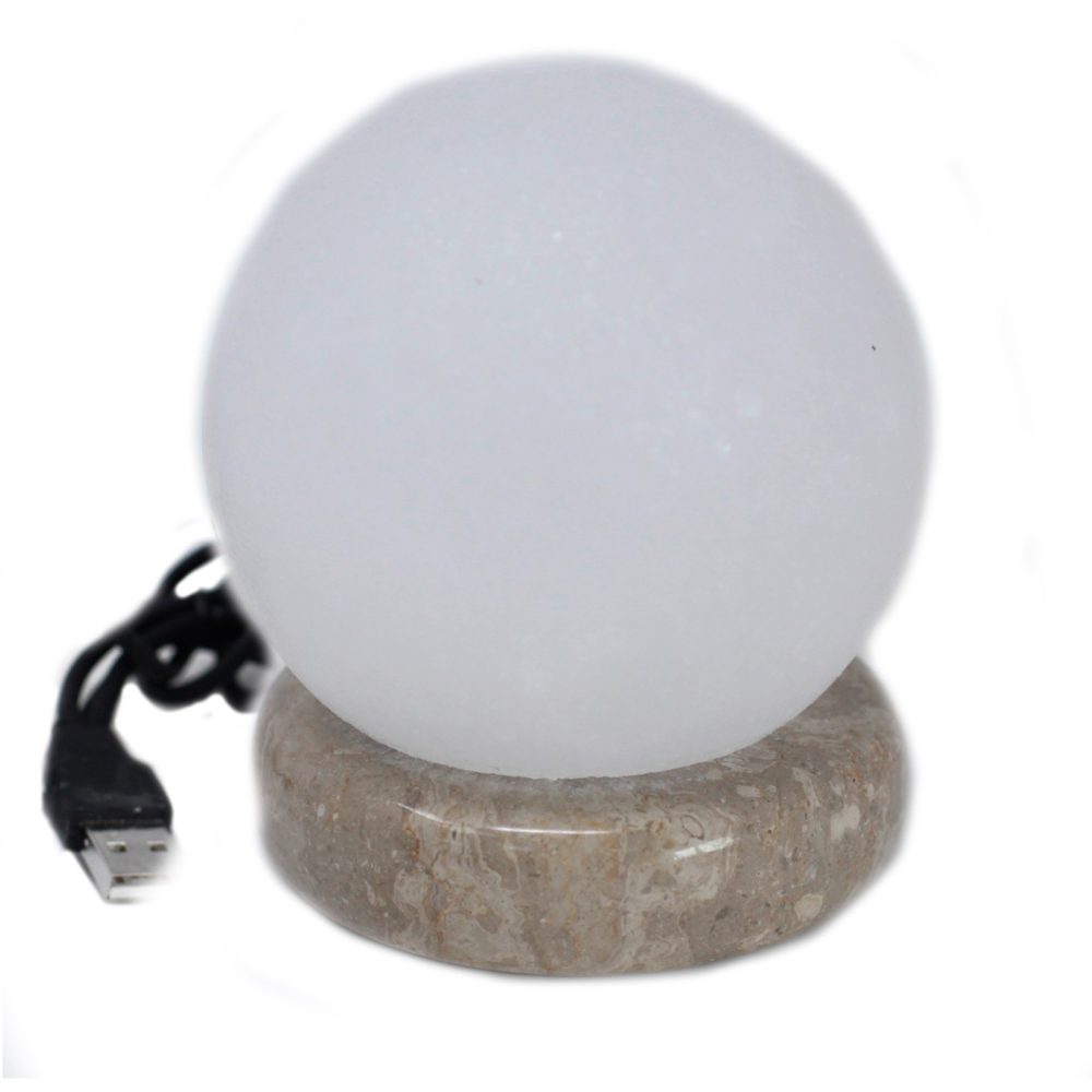 A round, white light sphere sits on a marble base, connected to a black USB cable, against a plain white background.