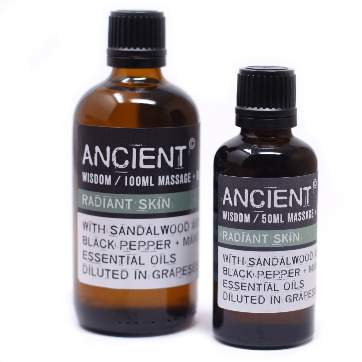 Two amber glass bottles stand on a white surface, each labeled "ANCIENT WISDOM / [size] MASSAGE RADIANT SKIN WITH SANDALWOOD BLACK PEPPER + MA ESSENTIAL OILS DILUTED IN GRAPES." One bottle is 100ml, and the other is 50ml.