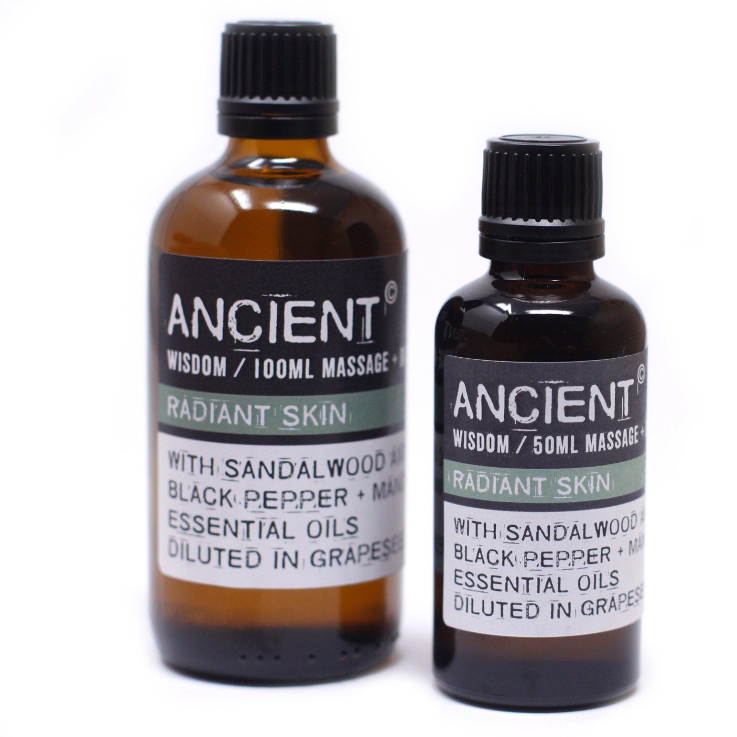 Two amber glass bottles stand on a white surface, each labeled "ANCIENT WISDOM / [size] MASSAGE RADIANT SKIN WITH SANDALWOOD BLACK PEPPER + MA ESSENTIAL OILS DILUTED IN GRAPES." One bottle is 100ml, and the other is 50ml.