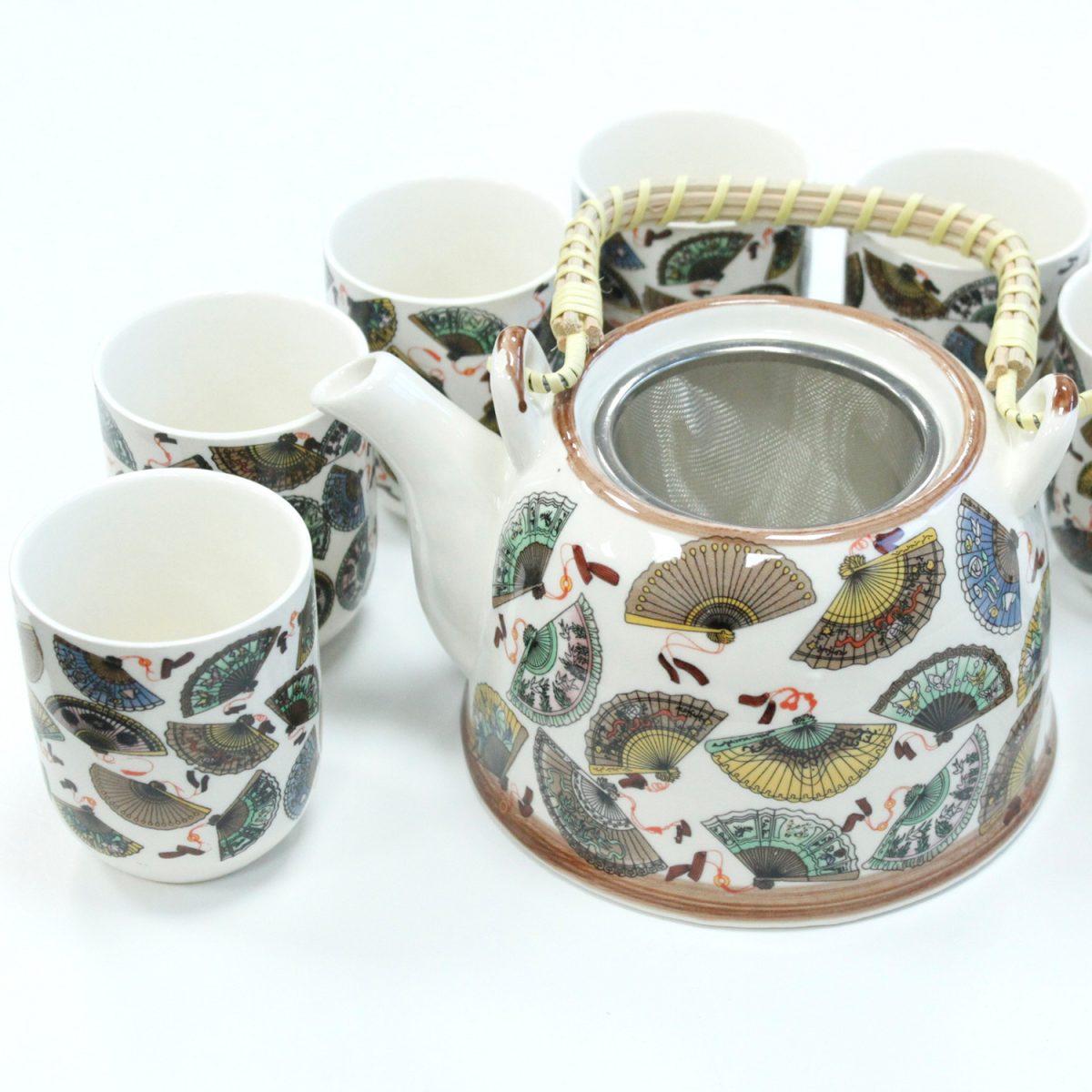 A ceramic teapot with a wicker handle sits beside six matching cups, all decorated with colorful fan illustrations, on a white surface.