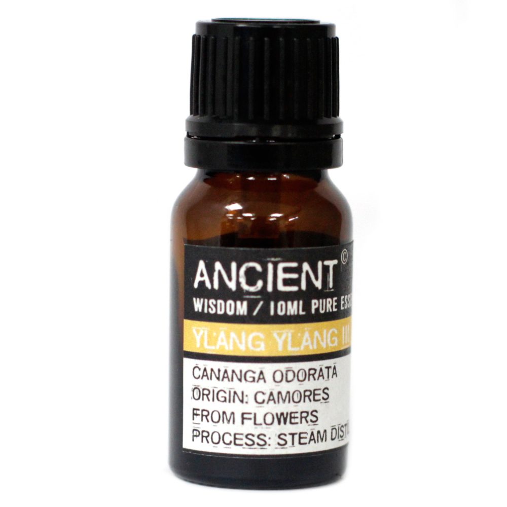 The brown, glass bottle holds "ANCIENT WISDOM/10ML PURE ESS" of "YLANG YLANG" with "CANANGA ODORATA," its origin, "CAMORES," "FROM FLOWERS," by "PROCESS: STEAM DIST." it is placed on a white background.