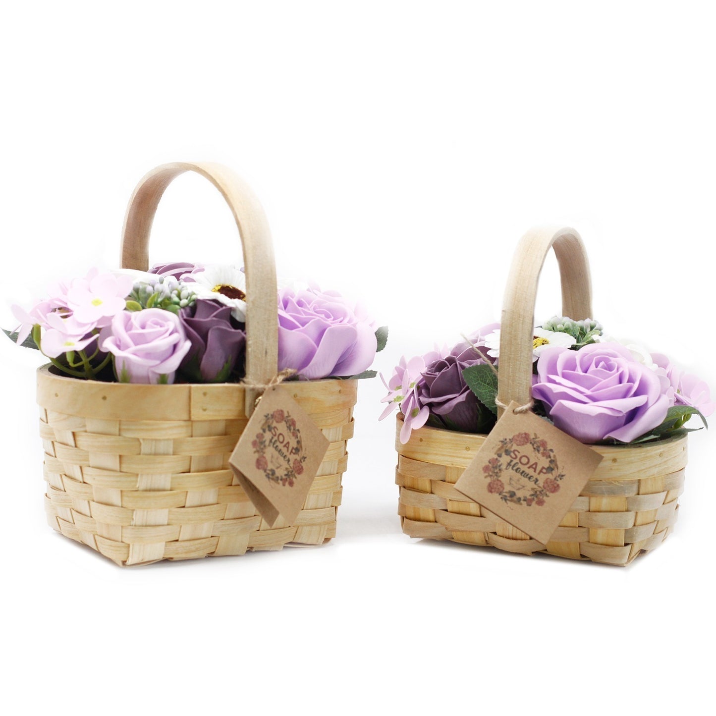 Two wicker baskets hold soap flowers with lavender and purple roses. Brown tags hang from each with the text "SOAP flower" arranged around a floral wreath on them. The background is white.