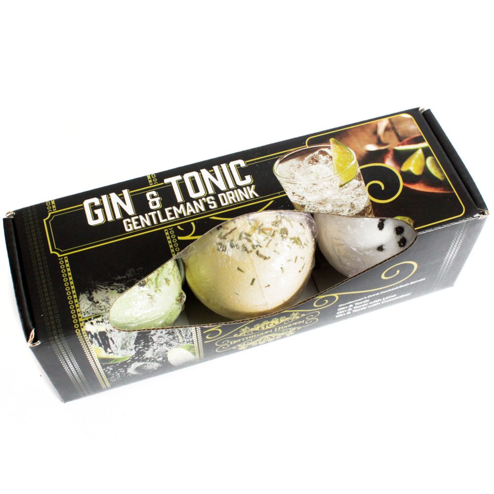 Three bath bombs are nestled inside a black box.  The box depicts a gin and tonic and is labeled "GIN & TONIC GENTLEMAN'S DRINK".  The bath bombs are various pale colors.