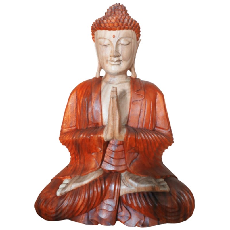 A wooden sculpture of a seated figure with hands in prayer position, wearing a detailed robe. The figure sits cross-legged, radiating tranquility and focus in a serene environment.