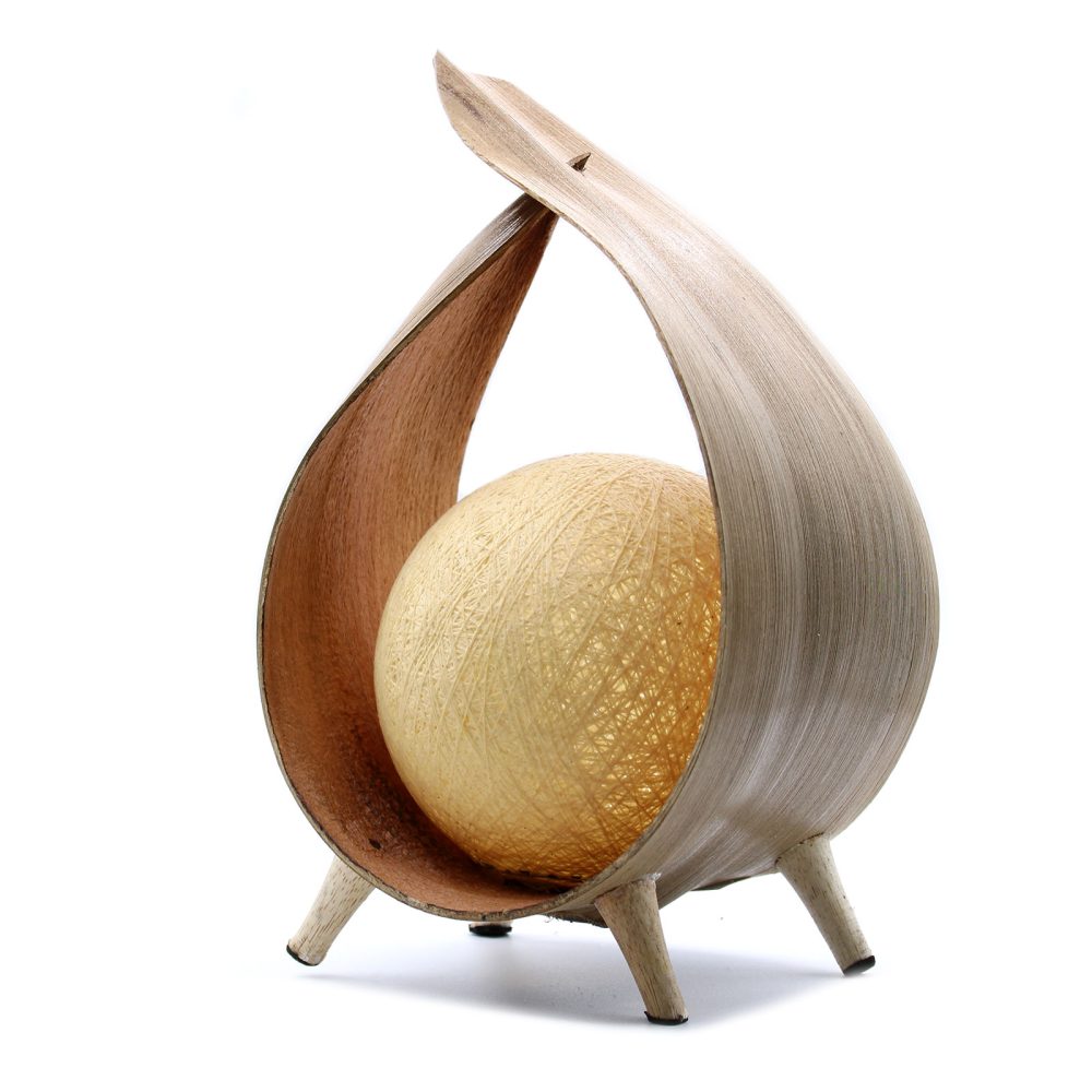 A pale, spherical lamp sits nestled within a wooden, leaf-shaped frame on short legs against a white background.