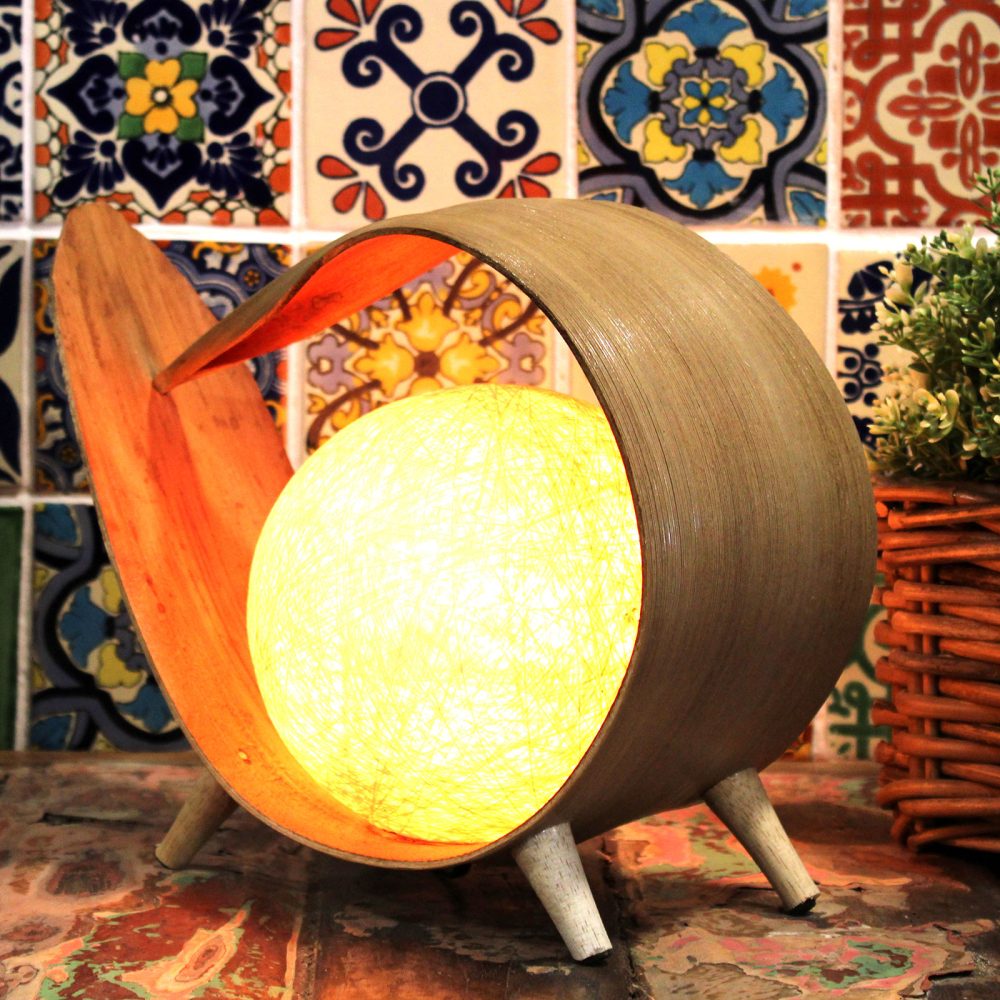A bamboo lamp illuminates a spherical light source.  It sits on a multi-colored tiled surface.