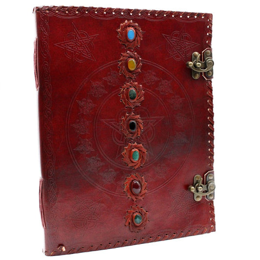 A red leather book, secured with metal clasps and a stitched edge, features a central pentagram design with inlaid gemstones and star details, all on a white background.