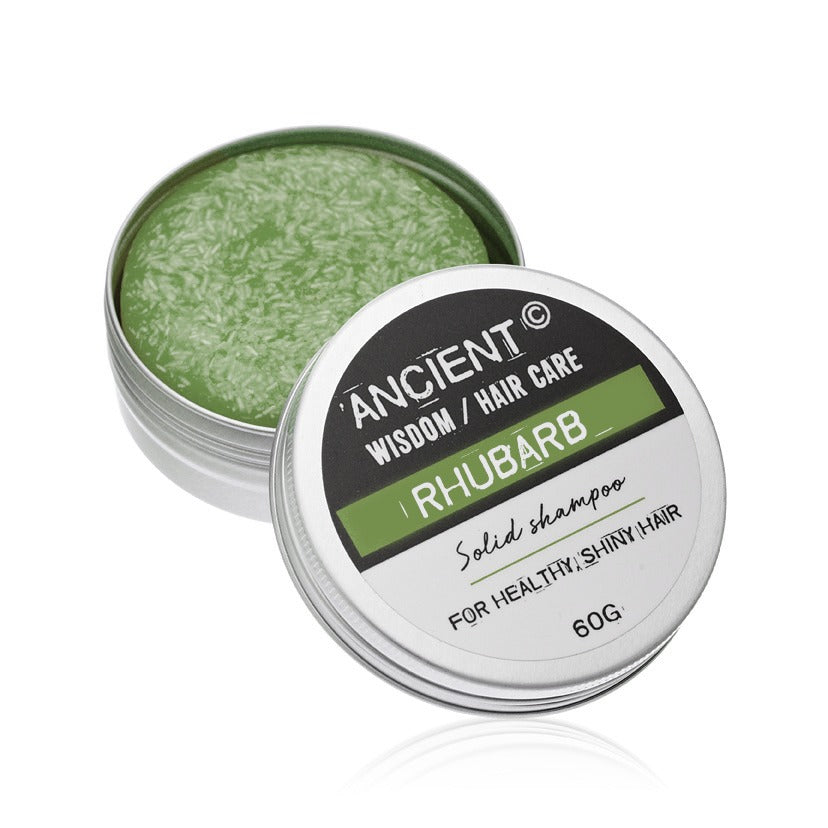 Solid green shampoo in silver tins sit on a white surface, one open and one closed. The lid reads: "ANCIENT WISDOM / HAIR CARE RHUBARB Solid shampoo FOR HEALTHY, SHINY HAIR 60G"